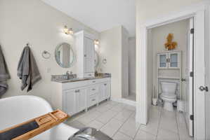 Bathroom featuring a freestanding soaking tub, double vanity with stone countertop, tile flooring, and a walk-in shower