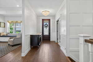 Hardwood flooring extending through the entry, detailed wainscoting, and a decorative crystal chandelier