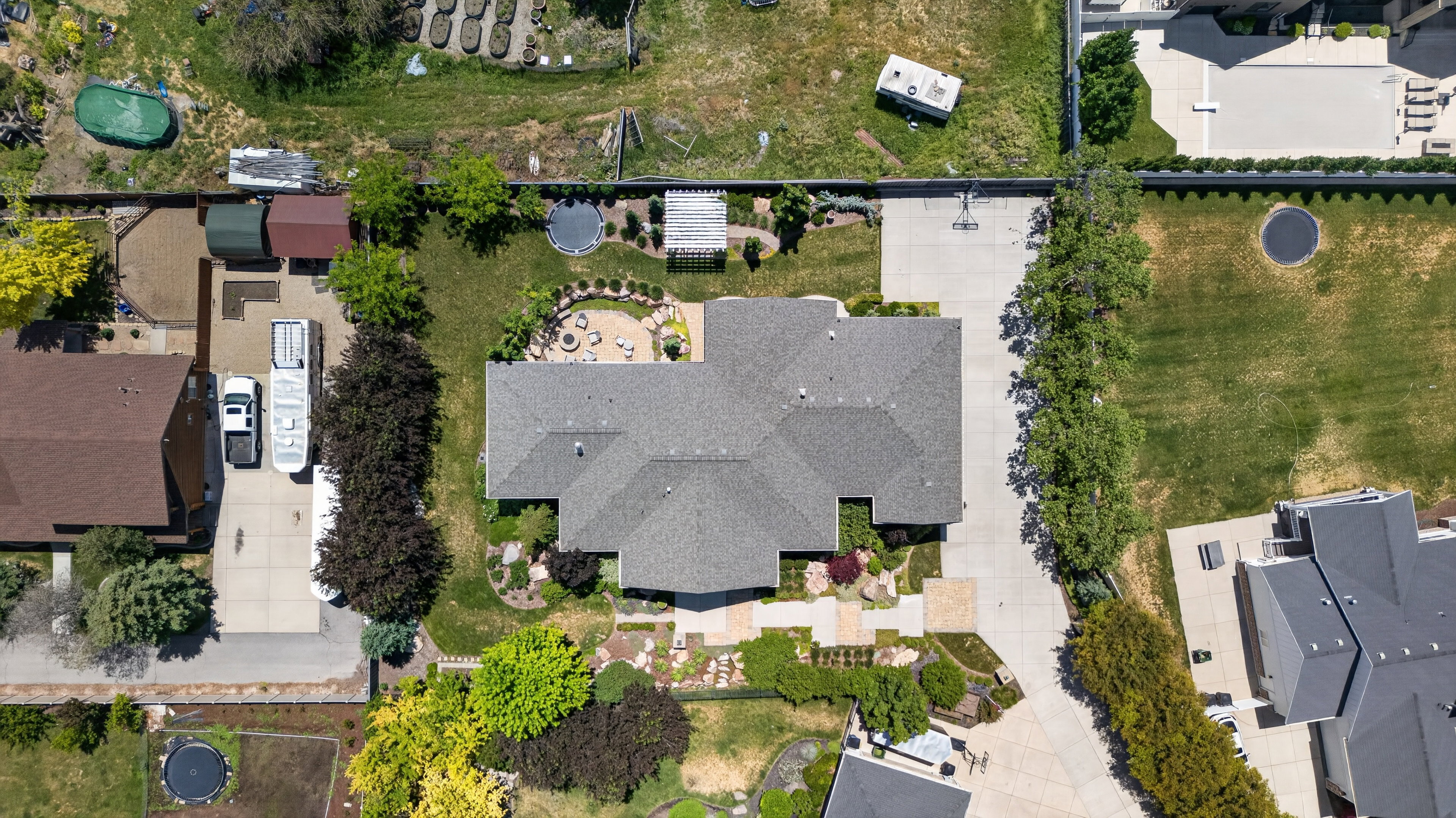 The property features a large main residence with a gabled roofline, extensive paved areas, and mature landscaping