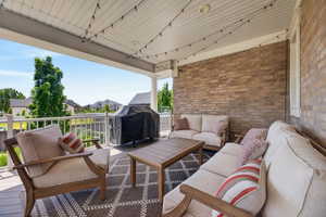 Expansive covered patio featuring a brick exterior wall, white railing, outdoor ceiling fan, and string lights