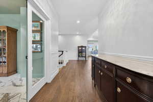 Expansive hallway featuring wood-finish flooring, white wainscoting, and recessed lighting
