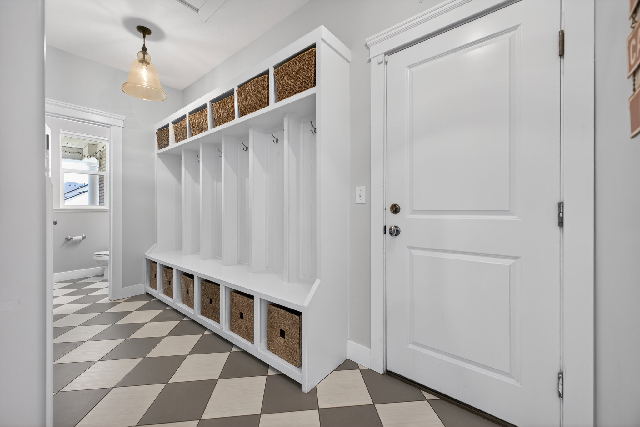 Custom built-in mudroom bench with cubbies and woven baskets provides ample storage