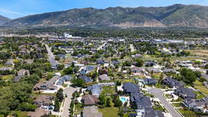 Expansive residential area featuring a diverse collection of homes, mature tree coverage, paved roads, and mountain backdrops