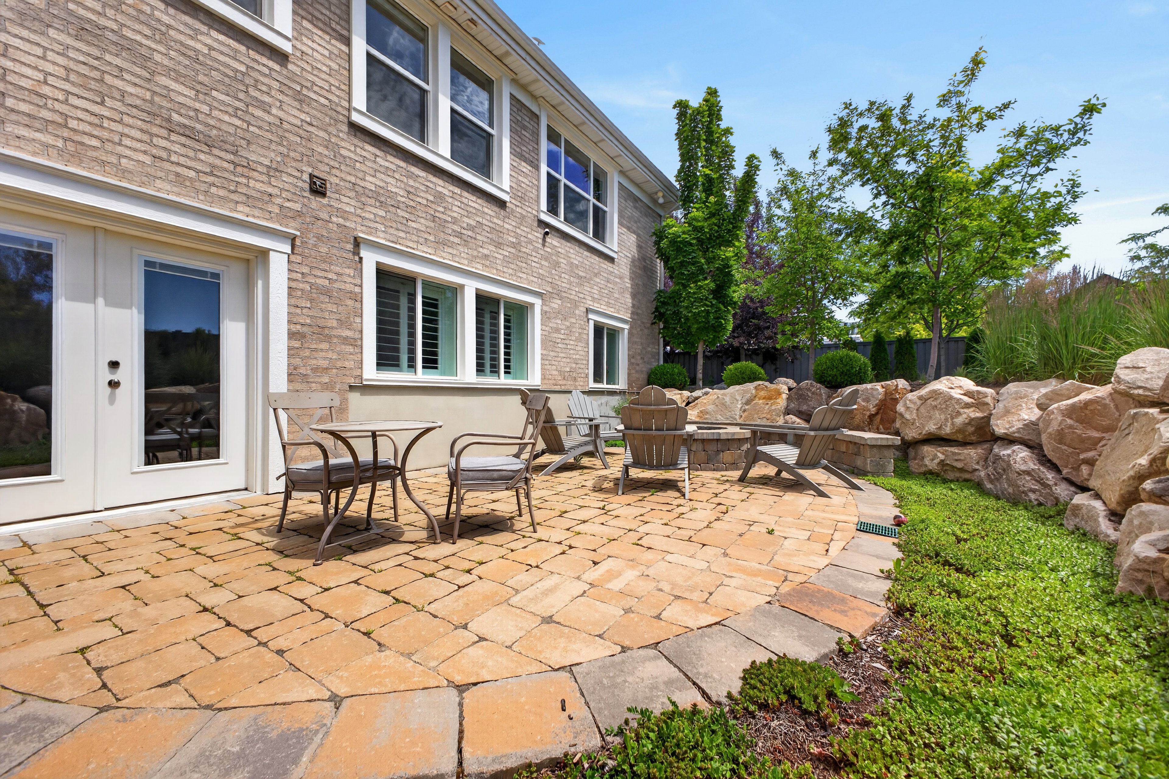 Patio area featuring paver stone flooring, a built-in fire pit, and a stone retaining wall