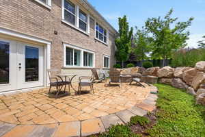 Patio area featuring paver stone flooring, a built-in fire pit, and a stone retaining wall
