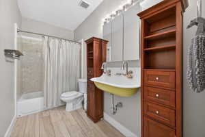 Bathroom featuring a wall-mounted sink, dual wall-mounted faucets, and two tall wood-finish storage cabinets