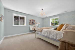 Room featuring neutral-toned carpeting, light blue walls with decorative stenciling, white trim, and two windows
