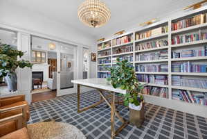 Custom built-in shelving with integrated lighting, glass pocket doors, and a decorative chandelier