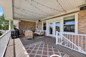 Expansive covered deck featuring composite decking, white railing, and a brick exterior