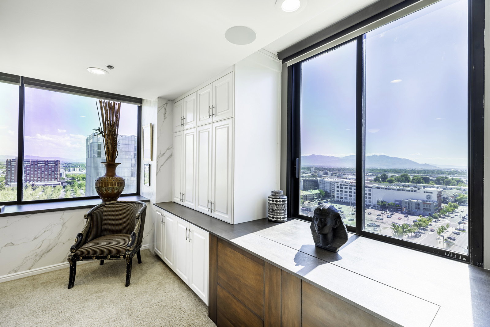 Expansive floor-to-ceiling windows frame the cityscape and distant mountains