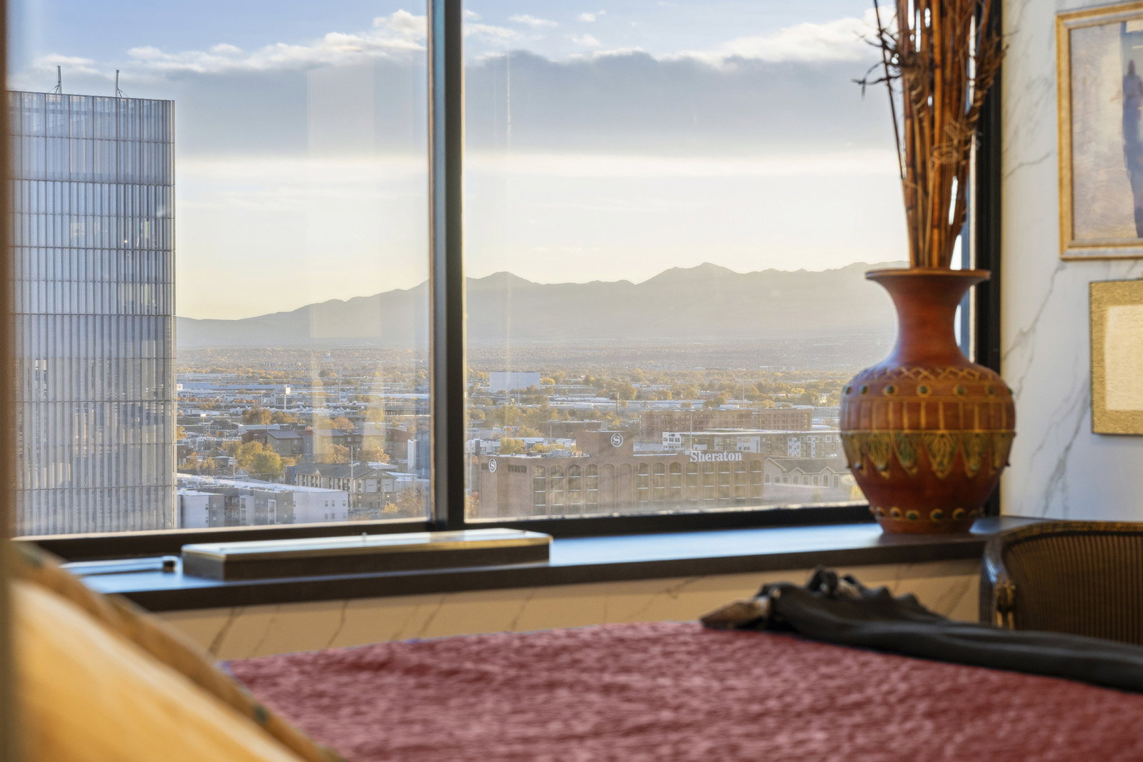 Floor-to-ceiling windows with a dark frame, a deep window sill, and a dark-toned wall featuring framed art