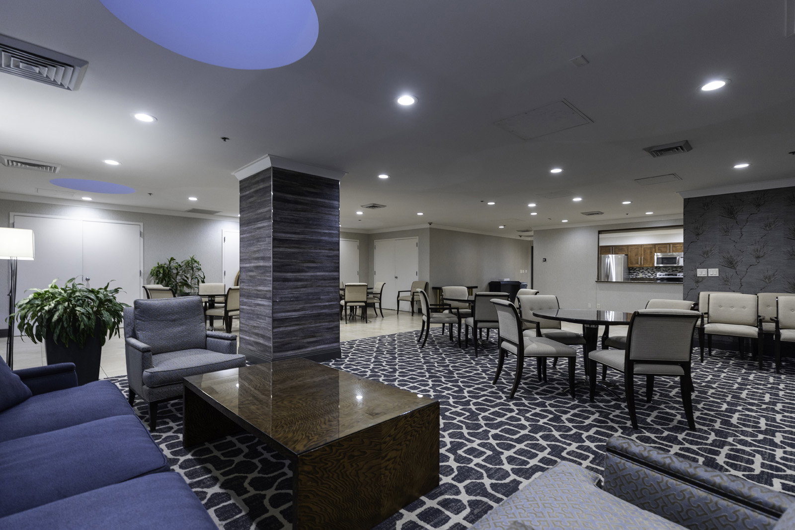 Spacious common area featuring patterned carpeting, recessed lighting, and a textured accent wall