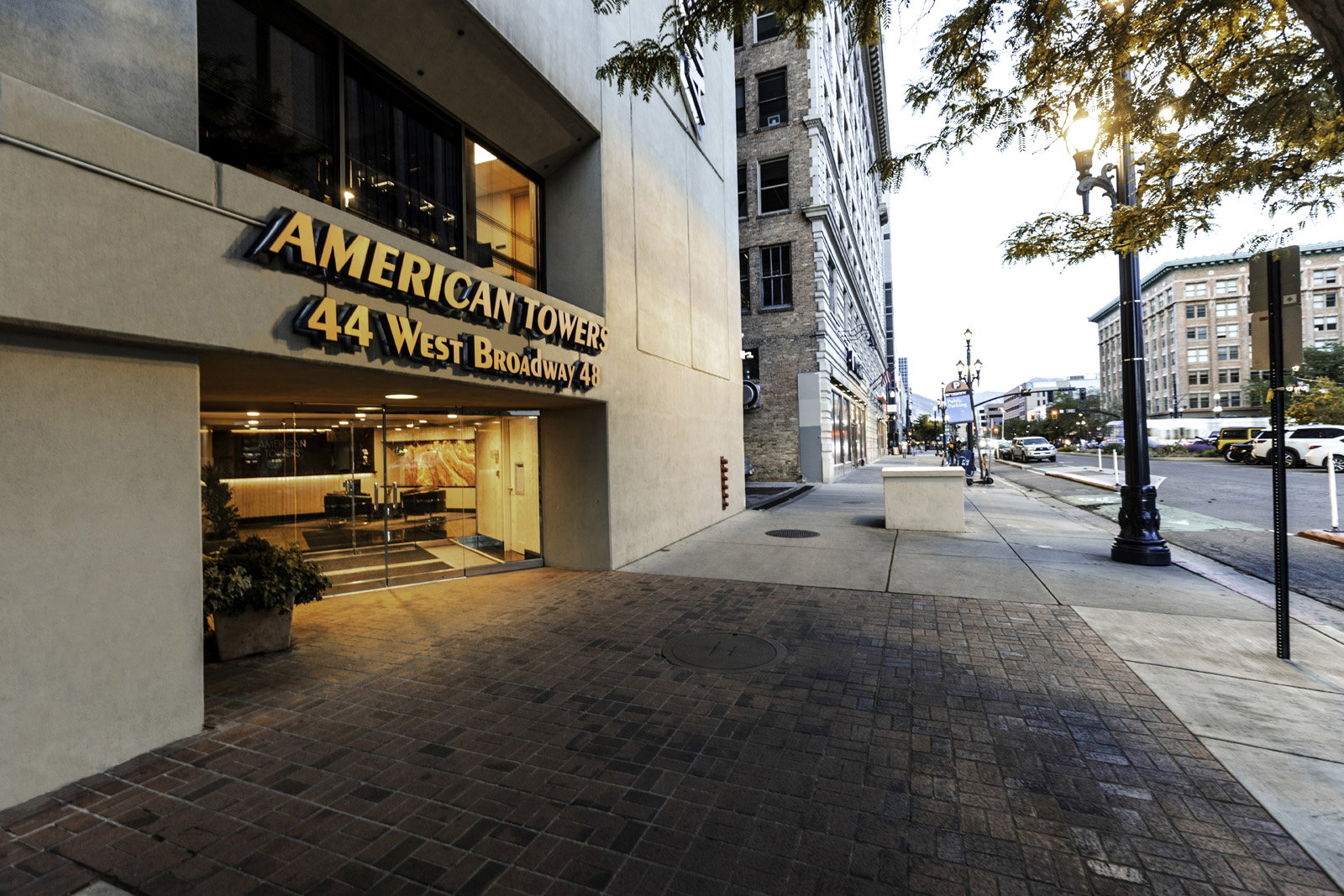 American Towers building entrance with prominent signage, a glass door entry, and a textured brick paver walkway