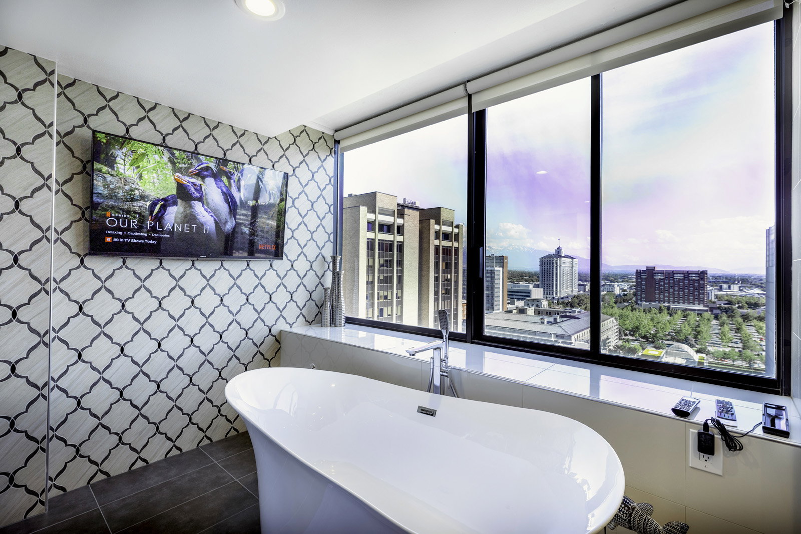 Freestanding soaking tub with a floor-mounted faucet, complemented by a full-height decorative tile accent wall