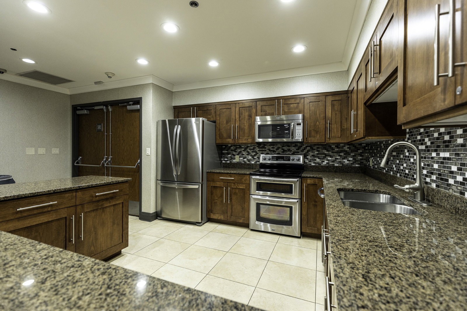 Well-appointed kitchen featuring granite countertops, a mosaic tile backsplash, stainless steel appliances, and extensive wood cabinetry