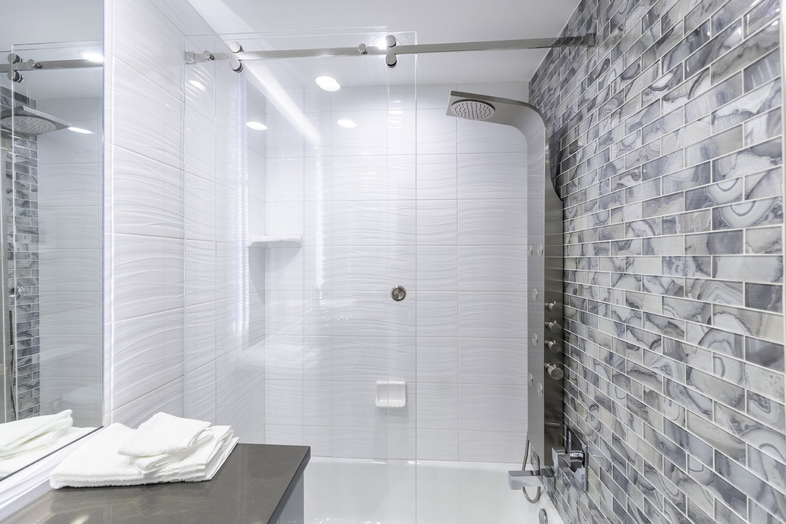 Sleek glass-enclosed shower with a multi-function shower panel