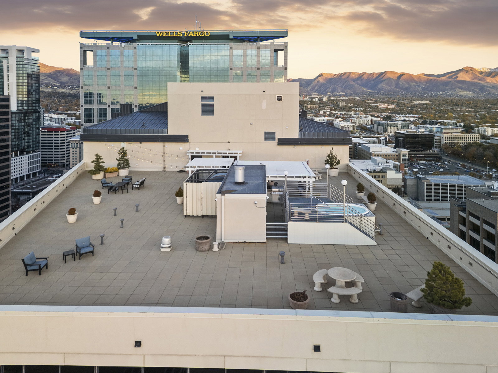Expansive rooftop terrace featuring a tiled surface, a built-in hot tub, and multiple seating areas