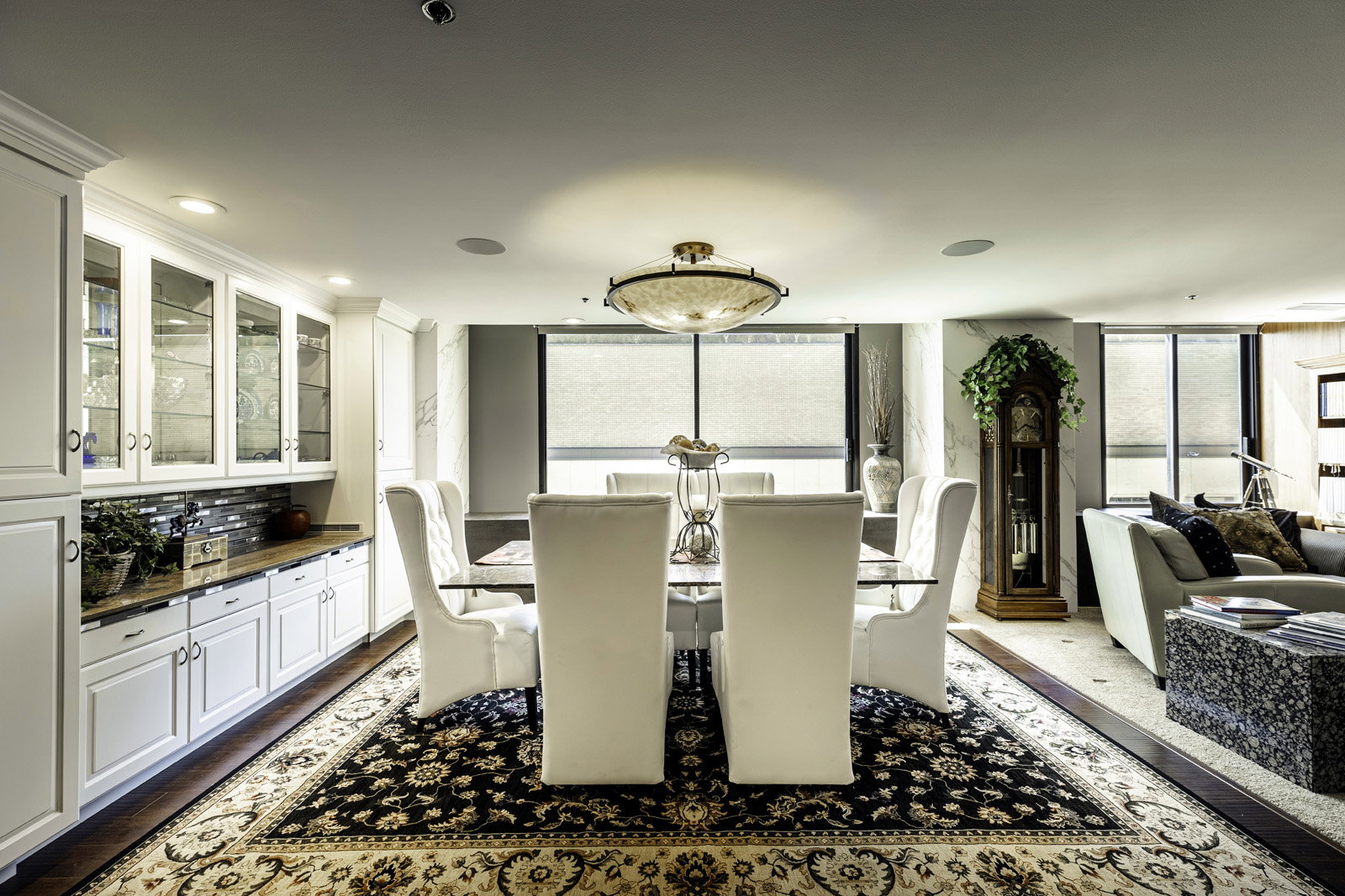 Dining area featuring a decorative ceiling light fixture, built-in cabinetry with glass-front uppers, a patterned area rug, and wood-finish flooring