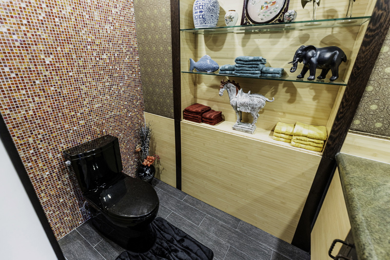 Powder room featuring a black toilet, mosaic tile accent wall, wood-finish flooring, and built-in shelving with glass shelves