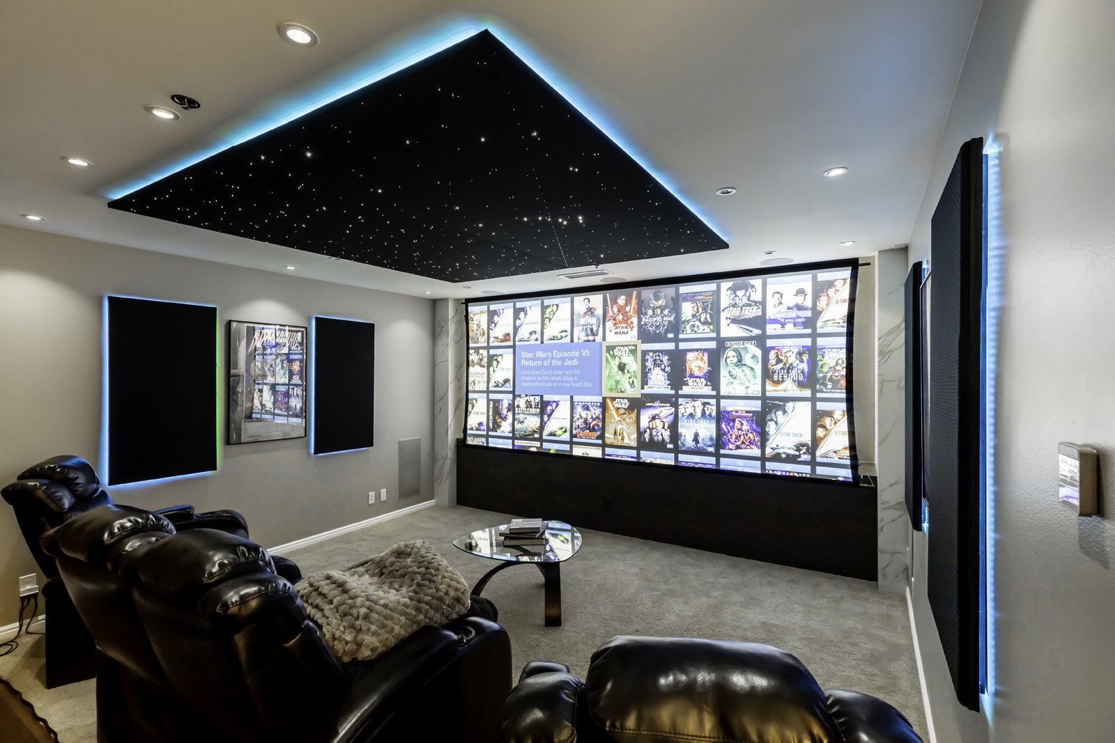 Dedicated media room featuring a large projection screen, recessed ceiling lighting, and a starfield ceiling with perimeter accent lighting
