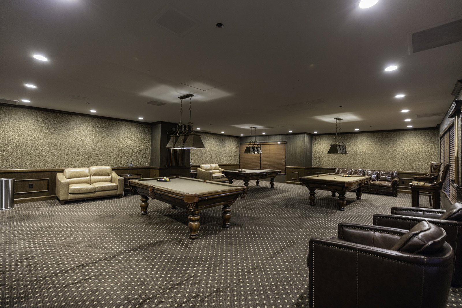 Spacious recreation area featuring patterned carpet flooring, recessed lighting, wall sconces, and crown molding