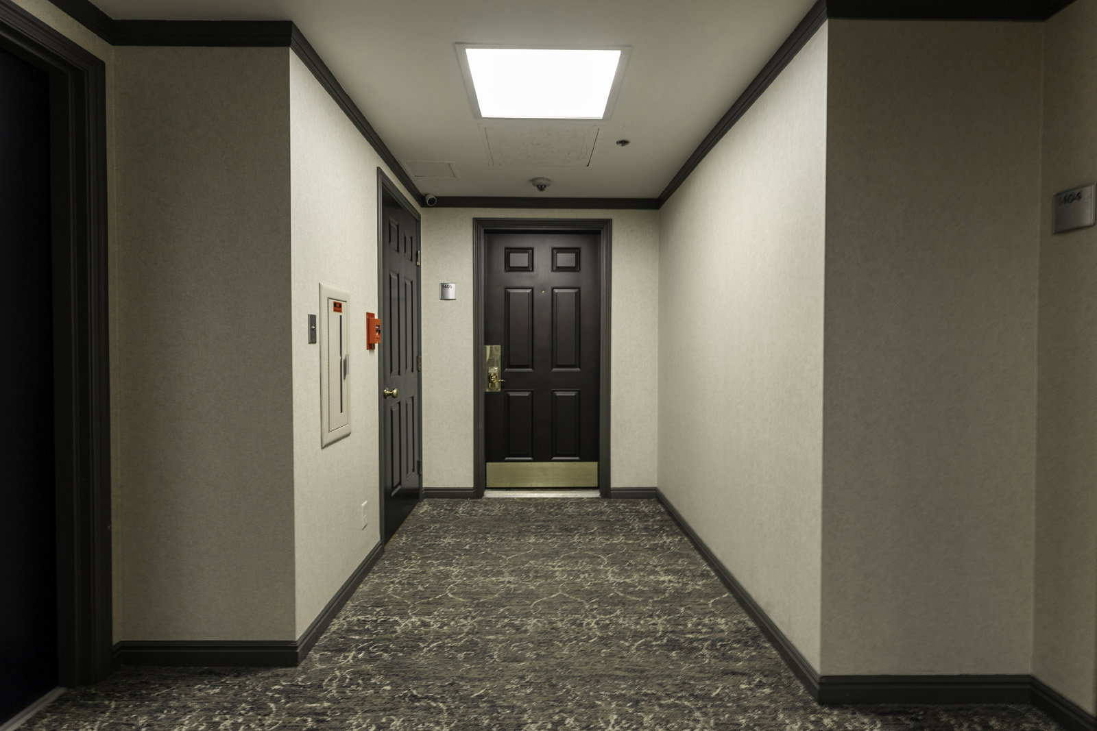 Hallway with patterned carpet flooring, light-toned walls, dark trim, and a recessed ceiling light