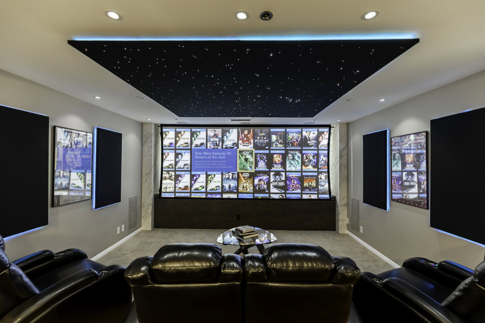 Dedicated media room featuring a starry night ceiling panel with accent lighting, large projection screen, recessed lighting, and wall-mounted acoustic panels with perimeter illumination