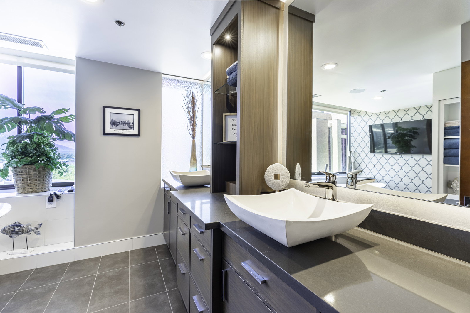Dual vessel sinks set atop a broad countertop with extensive cabinetry