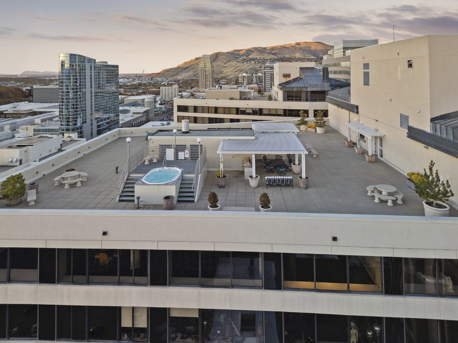 Rooftop patio with a built-in spa, shaded dining area, multiple seating arrangements, and large planters
