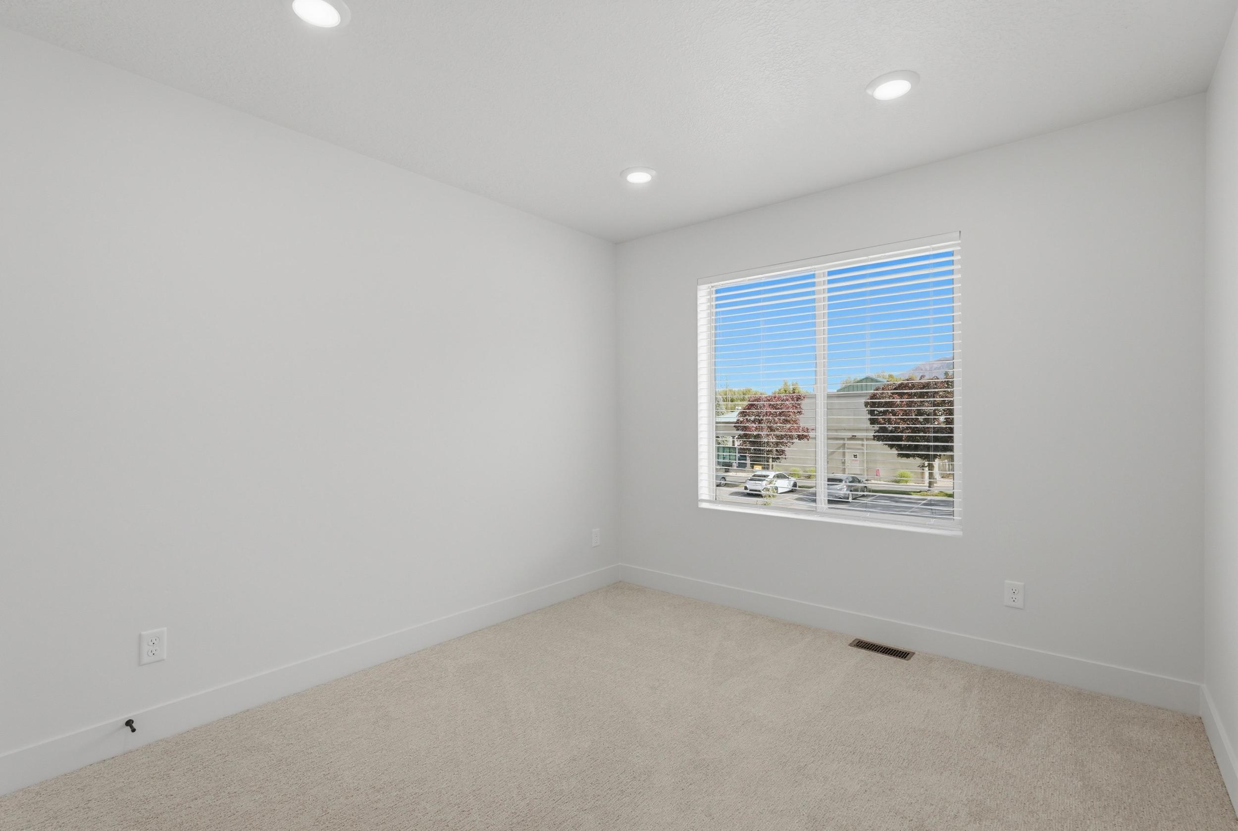 Bright room featuring recessed lighting, a large window with horizontal blinds, neutral wall paint, white trim, and light-colored carpet flooring