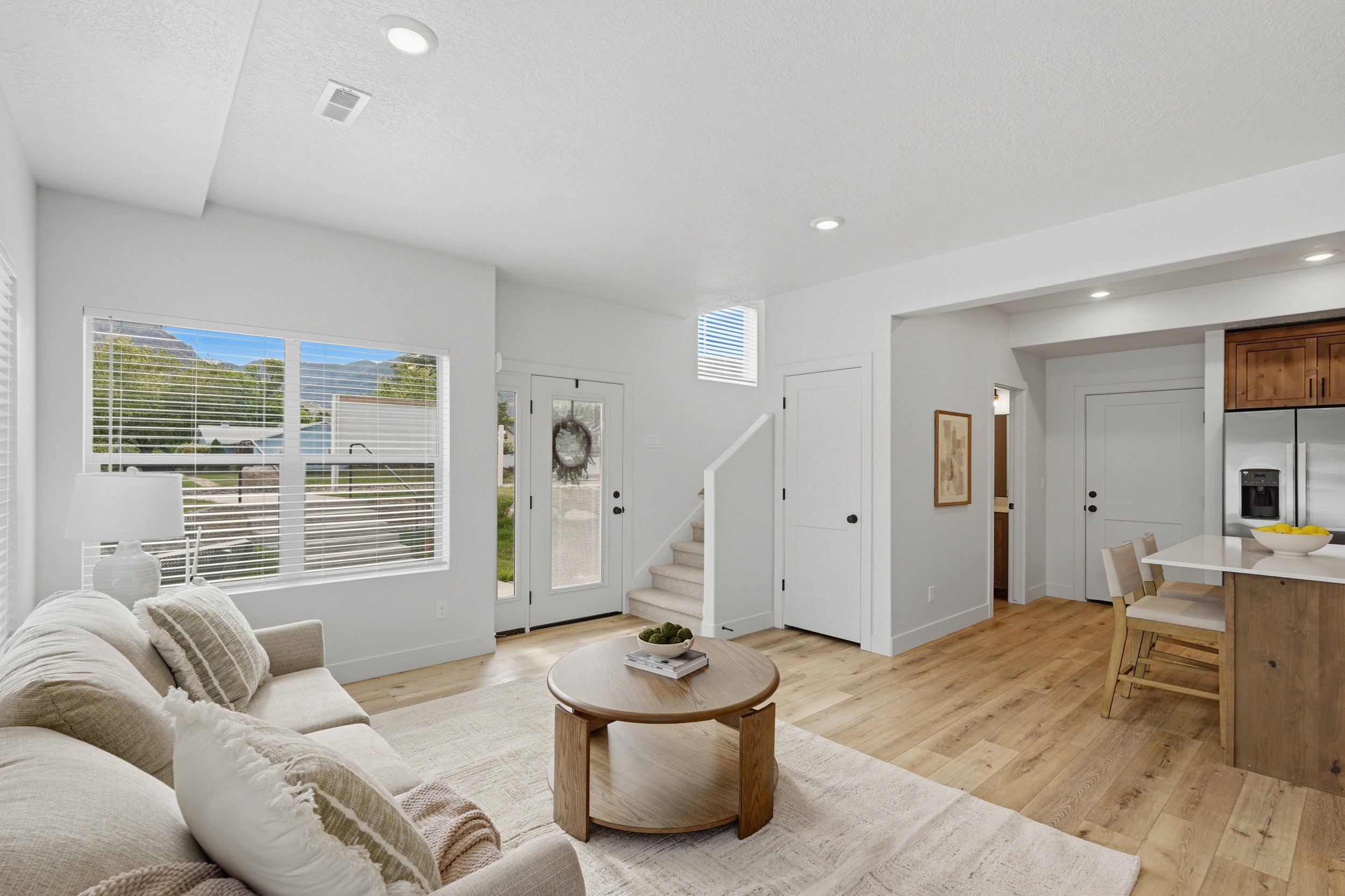 Light wood-finish flooring throughout the main living area, featuring recessed lighting and white painted walls