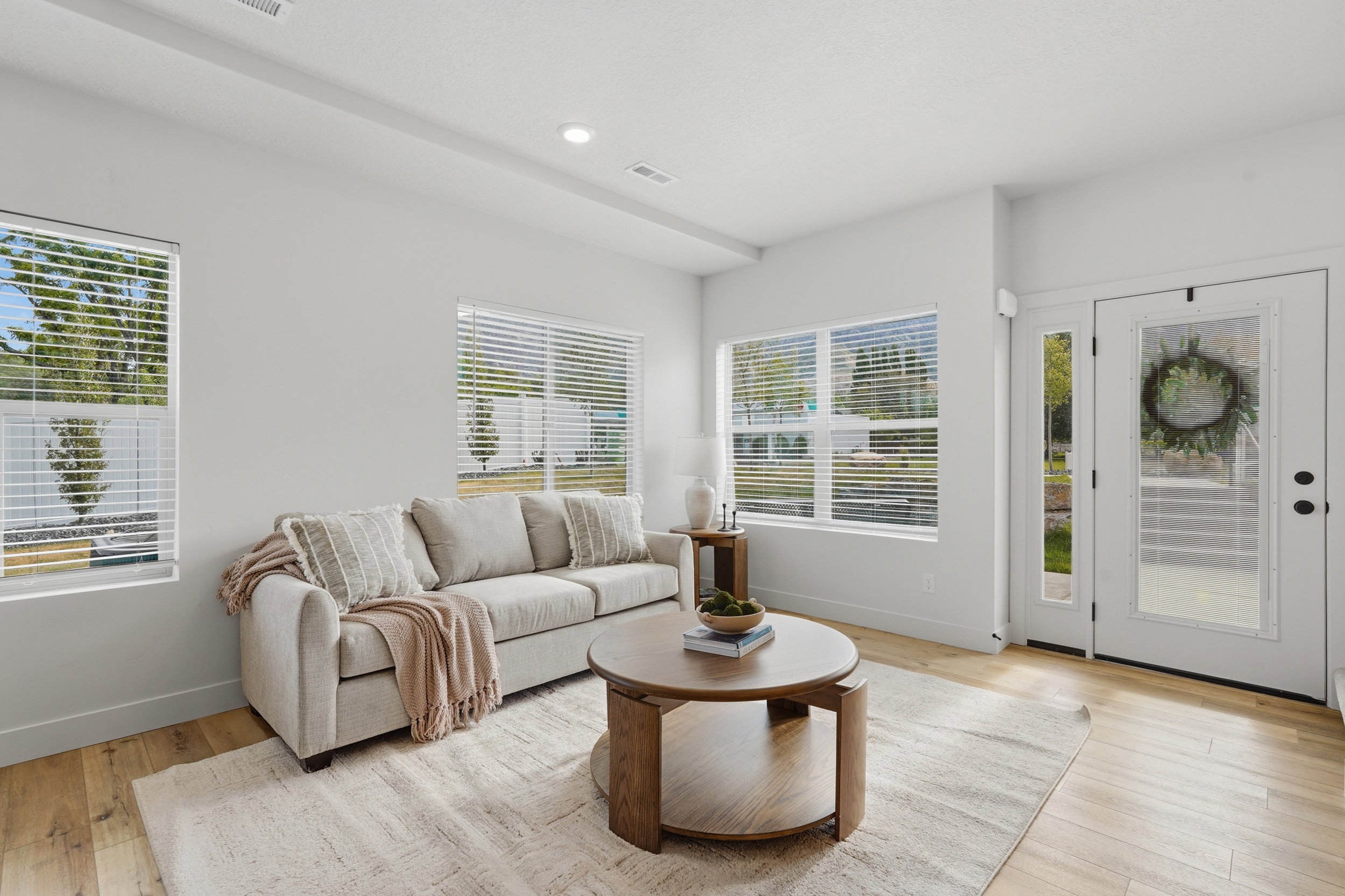 Bright living space featuring light wood-finish flooring, recessed lighting, and multiple windows