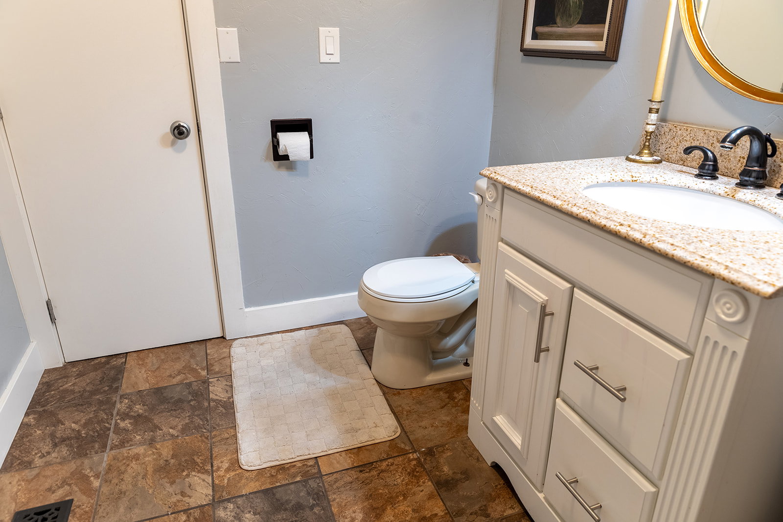 White vanity with a light speckled countertop, undermount sink, and dark bronze faucet