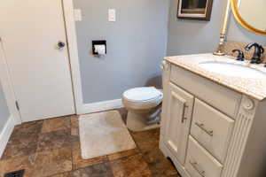 White vanity with a light speckled countertop, undermount sink, and dark bronze faucet