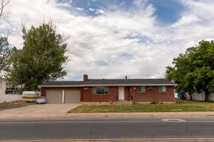 Brick exterior with a dark roofline, featuring a two-car garage, front entry door, and multiple windows