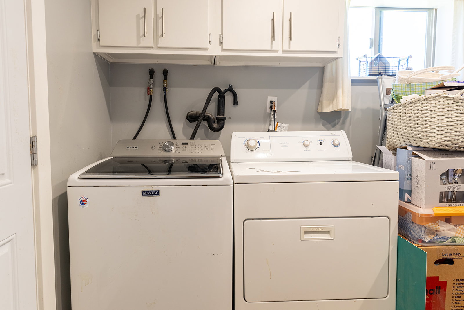 Dedicated laundry area featuring a white washing machine and dryer, overhead white cabinetry with brushed nickel hardware, and utility hookups