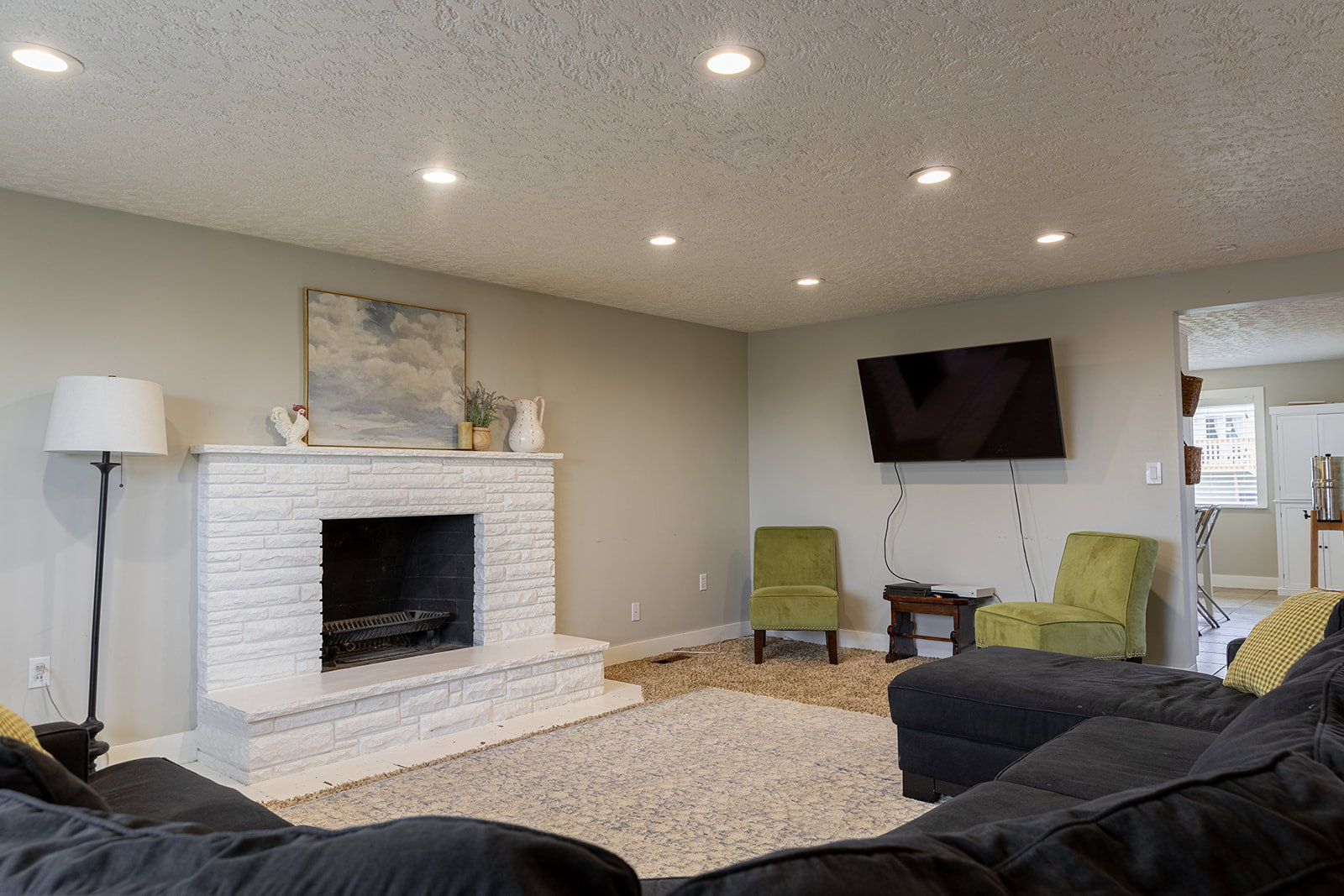 Living area featuring a painted brick fireplace with a raised hearth, recessed lighting, and wall-mounted television capability