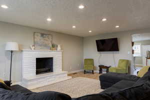 Living area featuring a painted brick fireplace with a raised hearth, recessed lighting, and wall-mounted television capability