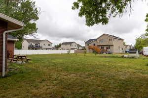 Spacious backyard featuring a large grassy area, a white privacy fence, and a multi-level wood deck with stairs