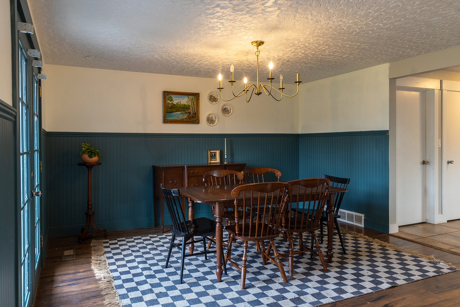 Dining area featuring wood-finish flooring, beadboard wainscoting, and a brass-tone chandelier