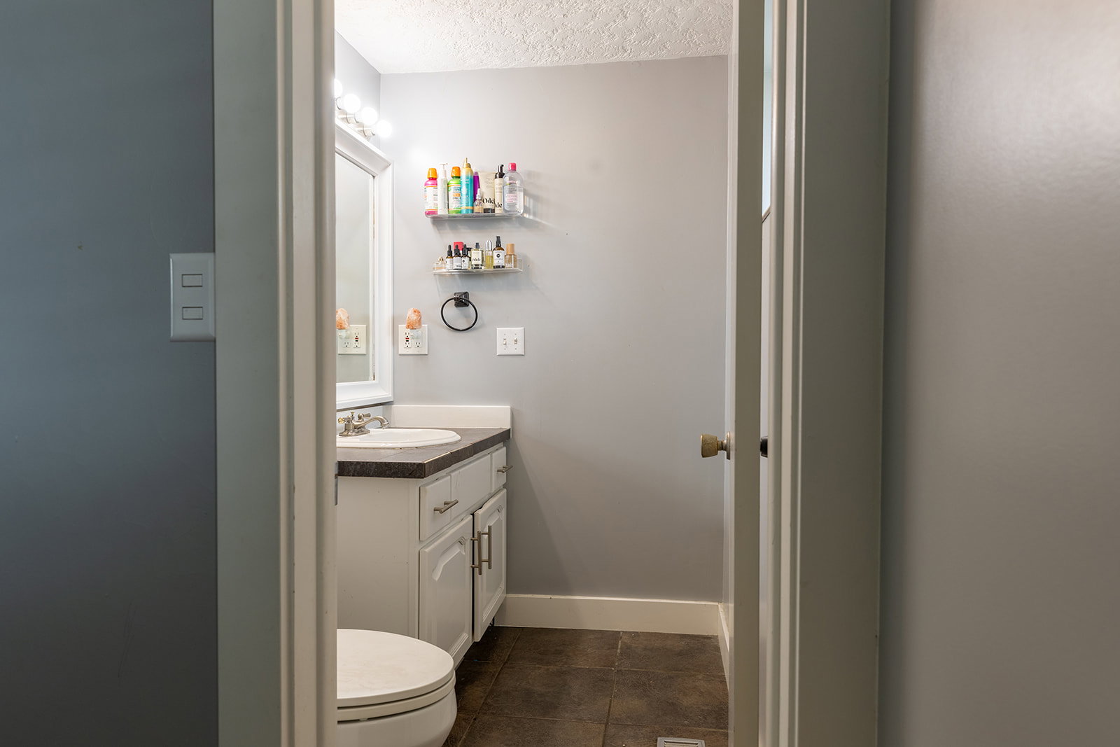 Bathroom featuring a white vanity with an undermount sink, dark countertop, and a mirrored medicine cabinet