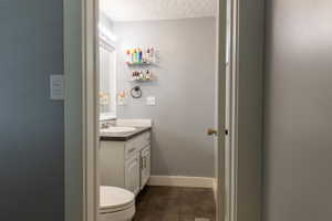 Bathroom featuring a white vanity with an undermount sink, dark countertop, and a mirrored medicine cabinet