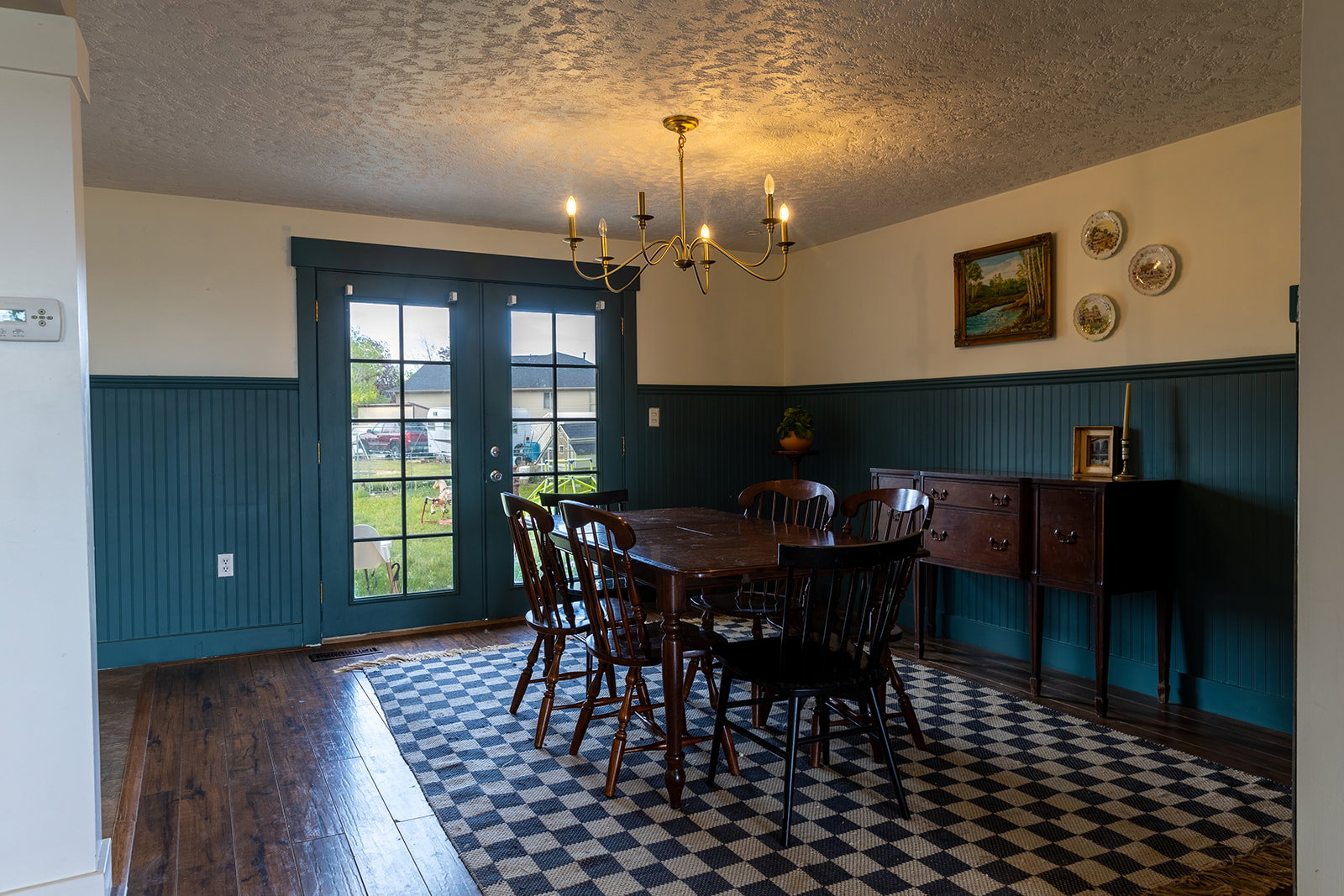 Dining area featuring beadboard wainscoting, wood-finish flooring, and a brass chandelier