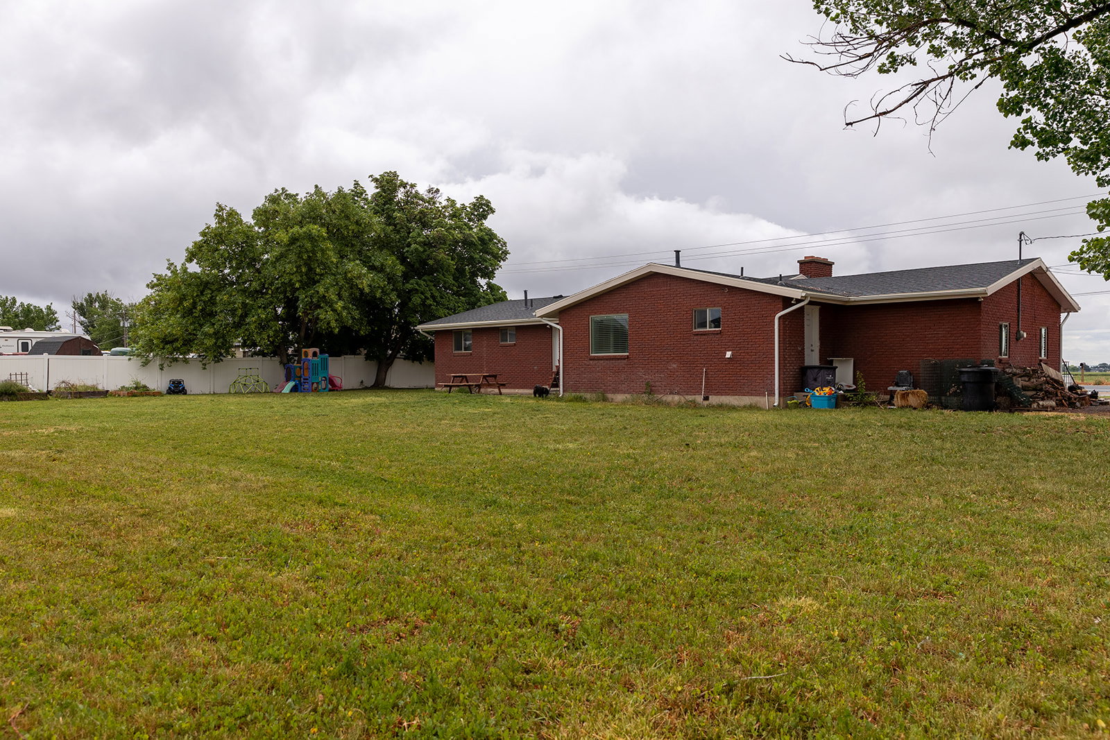 Expansive green lawn with mature trees and a white privacy fence