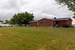 Expansive green lawn with mature trees and a white privacy fence