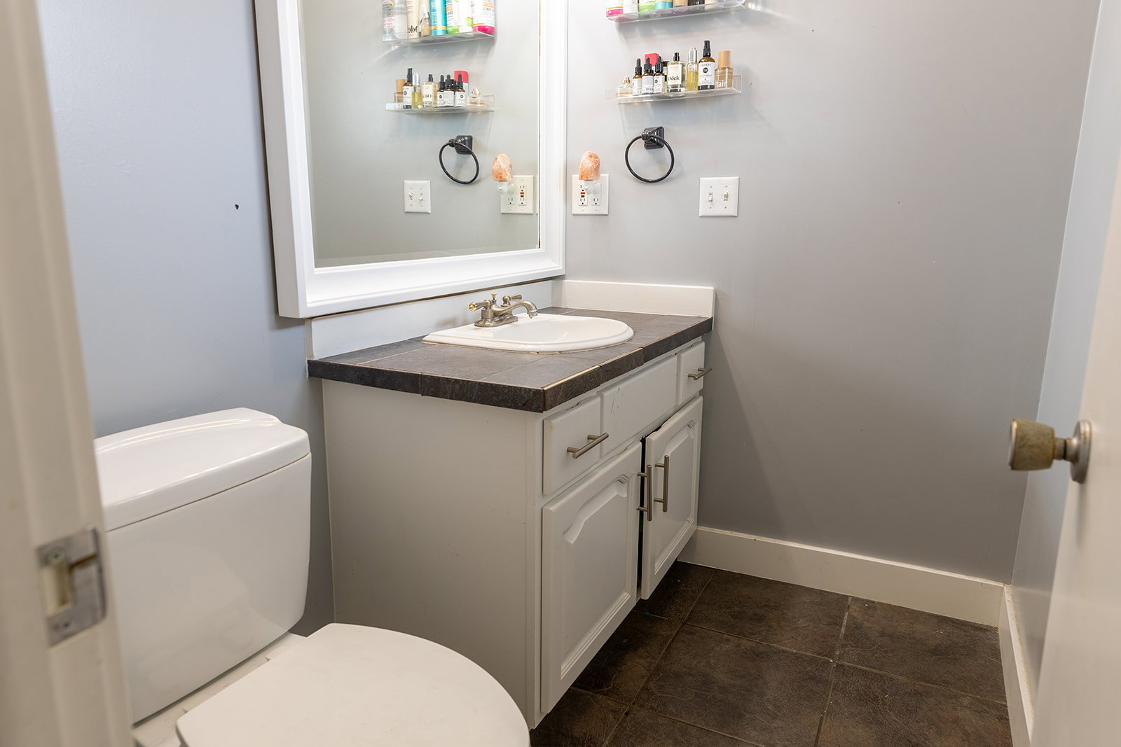 Bathroom featuring a white vanity with an integrated sink and dark countertop