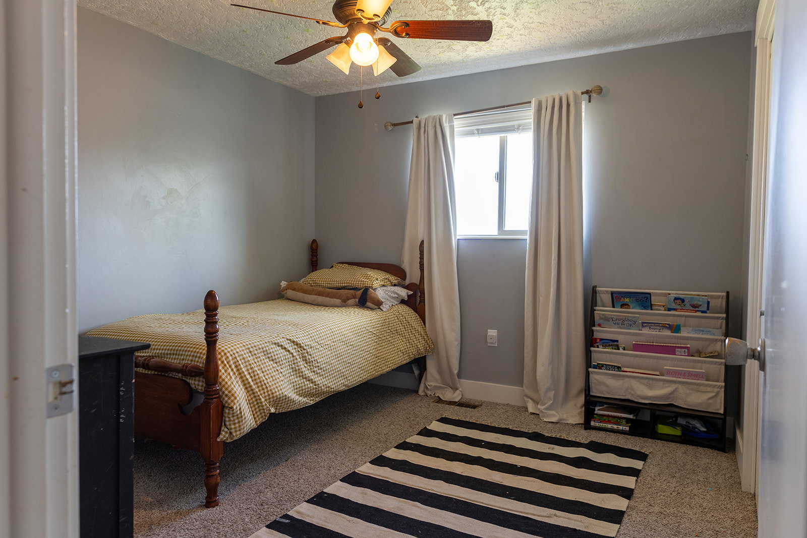 Room featuring light gray walls, carpeted flooring, and a ceiling fan with integrated lighting