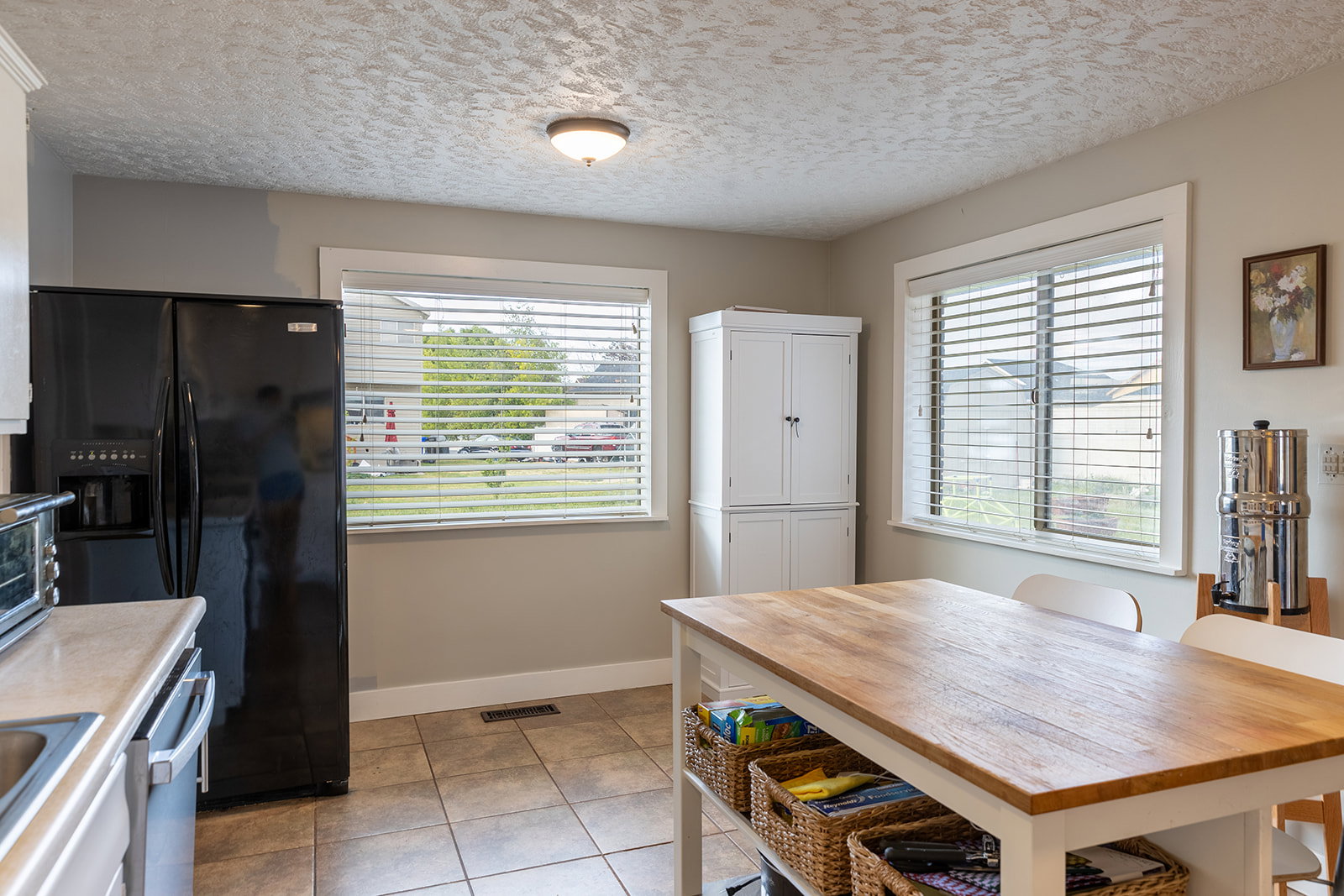 Kitchen dining area featuring a light wood-finish island, white base, and integrated storage