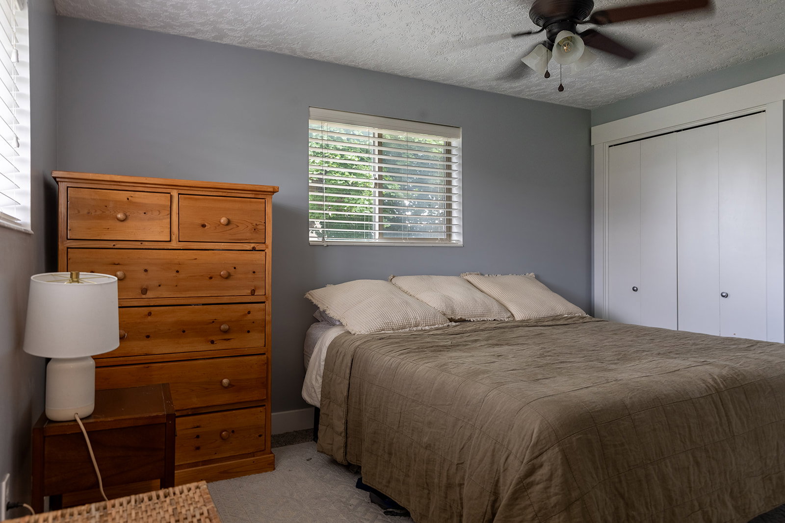 Bedroom featuring light gray walls, a window with horizontal blinds, and a ceiling fan with integrated lighting