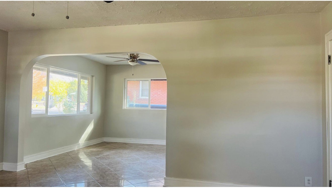 Archway opening to an interior space featuring multiple windows, a ceiling fan, and tile flooring